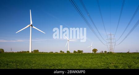 Windkraftanlagen stehen in Ackerland neben National Grid Hochspannungsleitungen in der Nähe von Alveston in South Gloucestershire. Stockfoto