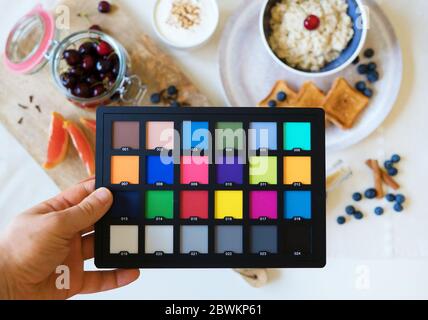 Professionelle Food-Fotografie. ColorChecker Farbdarstellung Diagramm in Assistentenhand. Stockfoto