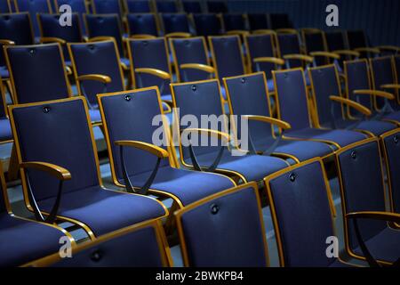 Reihen nummerierter leerer Zuschauerplätze aus Holz und blauer Polsterung für Theater, Präsentation oder Konzertveranstaltung, ausgewählter Fokus, schmale Tiefe von f Stockfoto