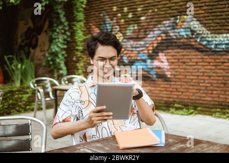 Lächelnder junger Mann, der Tablet-pc für die Arbeit verwendet Stockfoto