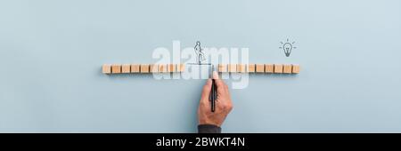 Männliche Hand zeichnet eine Verbindungslinie zwischen zwei Gruppen von Holzblöcken für einen Silhouetten Mann zu gehen über. Konzeptionelles Image von Teamwork und Innovation Stockfoto