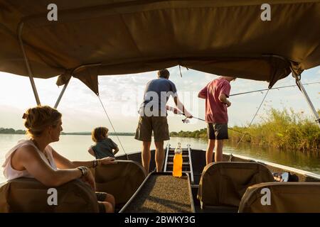Eine Gruppe von Touristen, Familie Angeln von einem Boot auf dem Zambezi River, Botswana Stockfoto