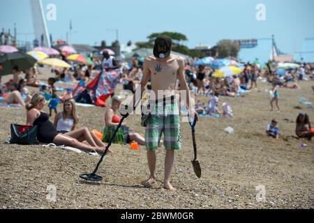 Ein Mann sucht am Strand von Southend-on-Sea in Essex nach Metall, da die Öffentlichkeit daran erinnert wird, nach der Lockerung der Lockdown-Beschränkungen in England soziale Distanzierungen zu praktizieren. Stockfoto