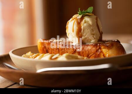 Nahaufnahme von französischem Toast mit Bananenscheiben und Eis in einem Café. Stockfoto