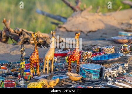 Handgefertigtes oder handgefertigtes afrikanisches Souvenir. Traditionelle Figur von einer Giraffe und andere Souvenirs in einem Massai-Markt verkauft. Tansania, Afrika Stockfoto