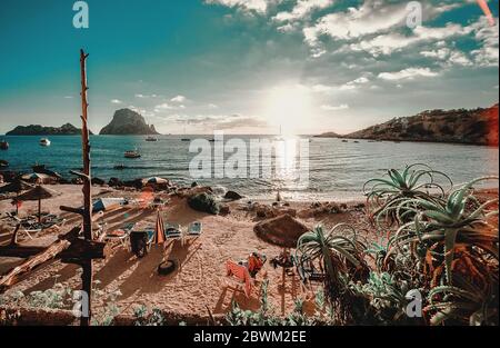 Malerische Landschaft idyllische Landschaftsfotografie wie Postkarte des leeren Cala d'Hort Beach, Es Vedra Blick auf die Klippen, Yachten im ruhigen Mittelmeer vertäut Stockfoto