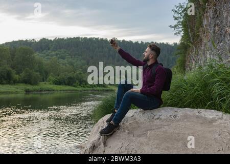 Junger Mann mit Handy, bärtiger Flusspferde, der selfie macht. Urlaub, Tourismus, Internet, Technologiekonzept. Stockfoto