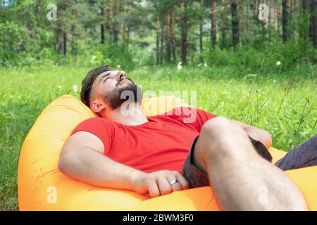 Junger bärtiger Mann kaukasischer Nationalität entspannend und genießen im Freien. Erholung, Stressabbau Stockfoto