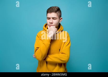 Ein junger Mann in einem Sweatshirt schaut zweifelhaft an Imaginäres Objekt zu seiner Linken Stockfoto