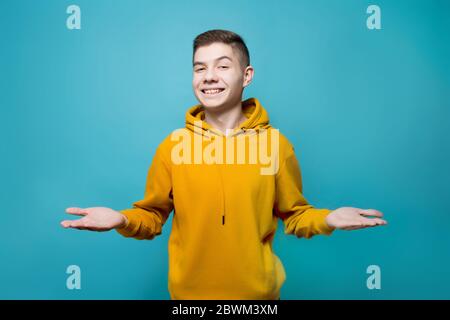 Der Kerl hält seine Hände mit den Handflächen nach oben und schaut lächelnd geradeaus Stockfoto