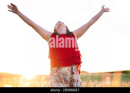 Junge Frau Arme erhoben bis zum Himmel, feiern Freiheit. Positive Emotionen Gefühl Lebenswahrnehmung Erfolg, Frieden des Geistes Konzept. Free Happy Girl im Sommer Wiese genießen Sonnenuntergang in der Natur. Stockfoto