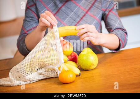 Eco-Packs. Frau Hand immer Früchte nach dem Einkauf aus Eco-Tasche. Kunststoffbeutel. Keine Verschwendung. Stockfoto