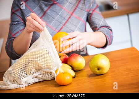 Eco-Packs. Frau Hand immer Früchte nach dem Einkauf aus Eco-Tasche. Kunststoffbeutel. Keine Verschwendung. Stockfoto