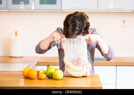 Eco-Packs. Frau Hand immer Früchte nach dem Einkauf aus Eco-Tasche. Kunststoffbeutel. Keine Verschwendung. Stockfoto