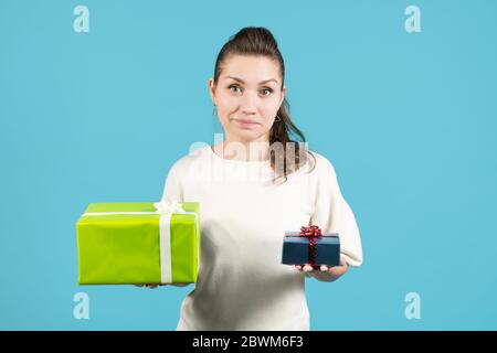 Das Mädchen hält vor ihren Händen ein großes und kleines Geschenk, grinst und schaut auf die Kamera Stockfoto