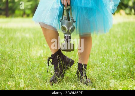 Frau in blauem Rock mit Gasmaske auf grünem Gras in einem Park stehend. Umweltschutz, Biohazard und ökologisches Konzept Stockfoto