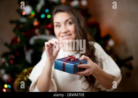 Junge Frau öffnet ein weihnachtsgeschenk, selektive Konzentration auf die Gegenwart Stockfoto