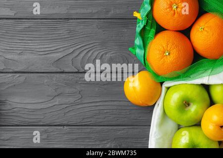 Äpfel und Orangen in Päckchen auf schwarzem Holztisch Stockfoto
