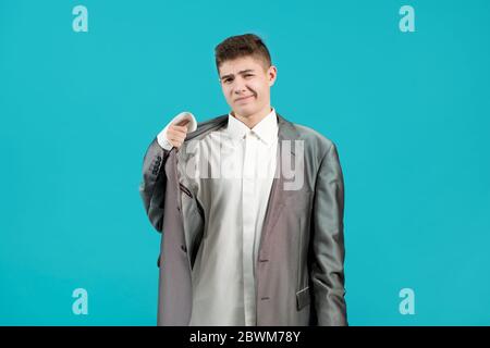 Der junge Mann äußert seine Unzufriedenheit darüber, dass er ein Hemd und eine Jacke eines Erwachsenen trug. Stockfoto