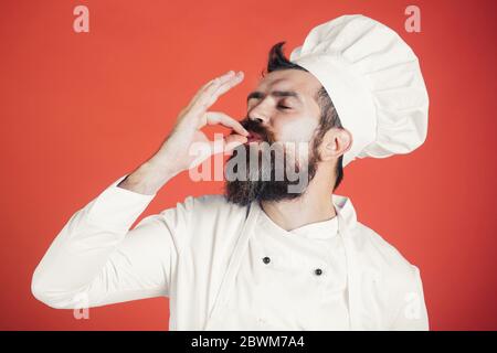 Professioneller Koch Mann zeigt Zeichen für lecker. Männlicher Koch in weißer Uniform mit perfektem Zeichen. Seriös zufrieden bärtige Koch, Koch oder Bäcker Gesturin Stockfoto