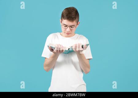 Nerd mit einer Brille, die ein Buch liest, hält es dicht vor sich Stockfoto