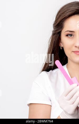 Porträt von Manikurist hält Maniküre Werkzeuge in den Händen tragen weiße Kleidung auf weißem Hintergrund mit Kopierraum. Stockfoto