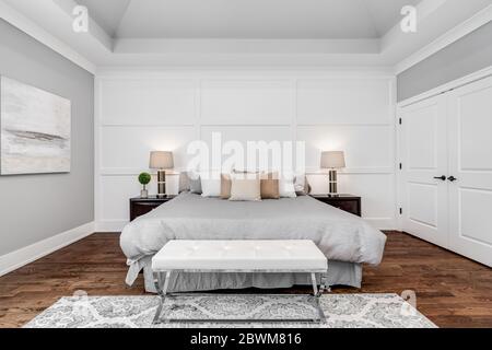 Ein neutrales, großes Hauptschlafzimmer mit hohen Decken und quadratischen Formen an der Wand. Stockfoto