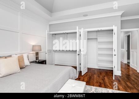 Ein neutrales, großes Hauptschlafzimmer mit hohen Decken und quadratischen Formen an der Wand. Stockfoto