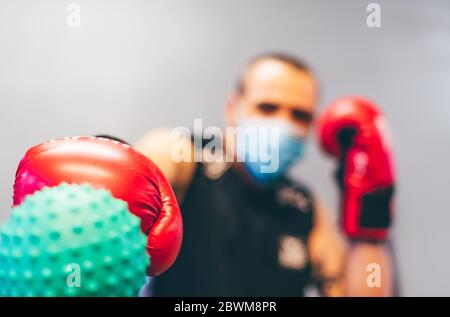 Boxer mit Maske und roten Handschuhen gegen Coronavirus. Konzept der Überwindung des Virus Stockfoto