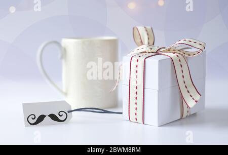 Tasse Kaffee am Morgen, Geschenkbox verpackt, Geschenkanhänger mit Symbol des Schnurrbart auf hellem Hintergrund mit Bokeh. Vatertag, Geburtstagskonzept Stockfoto