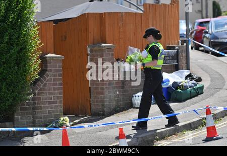 Ein Polizist legt Blumen in einem Haus in der Wessex Road in Salisbury, Wiltshire, nieder, wo zwei Frauen am Montag nach einer Störung starben. Ein Mann in den 30er Jahren wurde wegen Mordes verhaftet und in der Melksham Polizeistation in Gewahrsam genommen. Stockfoto