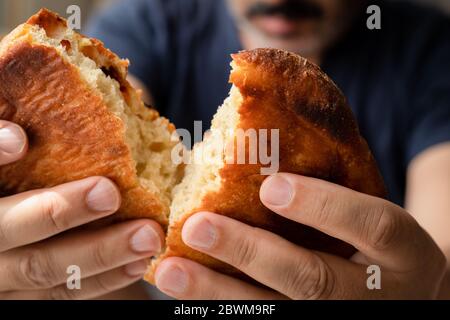 Frisch gebackenes Brot vom Bäcker. Bäcker hält frisches Brot in den Händen. Rustikaler Stil. Kurz bevor der hungrige Mensch Brot essen. Stockfoto