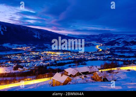 Hafjell, Norwegen. Luftaufnahme des Skigebiets Hafjell in Norwegen mit Skifahrern, die im Winter die verschneiten Pisten hinunterfahren, und Bergen in der Nacht Stockfoto