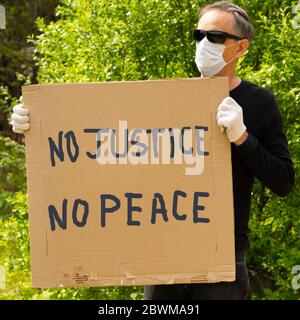 Ein weißer Mann hält ein Schild, das sagt: "Es gibt keine Gerechtigkeit, keinen Frieden" aus Protest gegen den Mord an George Floyd. Stockfoto