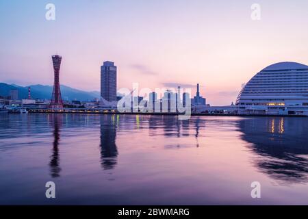 Kobe, Japan. Dämmerung in Kobe, Japan mit lila Himmel. Wolkenloser Himmel mit Hafen und Silhouetten zahlreicher Wolkenkratzer und Port Tower Stockfoto