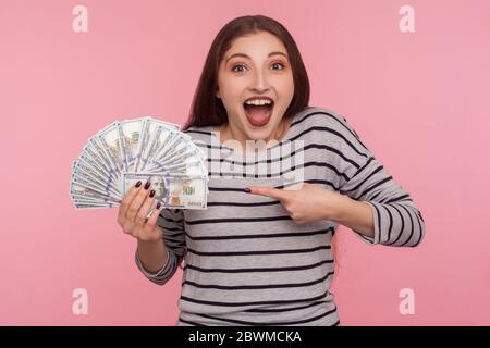 Porträt von extrem überglücklich erfreut junge Frau im gestreiften Sweatshirt schreien in Aufregung und zeigen Dollarscheine, schockiert durch Lotterie-Sieg, b Stockfoto