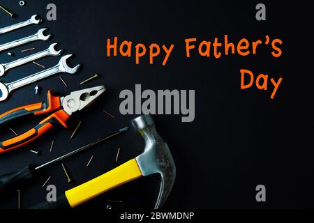 Bauwerkzeuge für die Renovierung von Zuhause orange und gelbe Farben auf schwarzem Hintergrund. Happy Vaters Day Konzept. Platz für Text, flaches Lay. Stockfoto