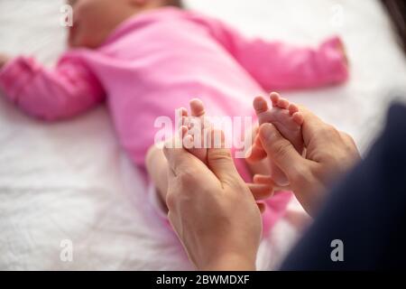 Mutter oder Arzt massieren den Fuß des kleinen Babys Stockfoto