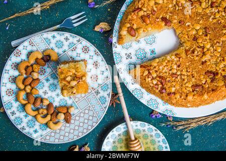 Türkische Kadayif mit Nüssen auf dem Tisch mit Honig Dipper Stockfoto