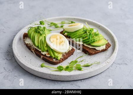 Avocado Sandwich mit gekochtem Ei - in Scheiben geschnittene Avocado und Ei auf Roggen gerösteten Brot für gesundes Frühstück oder Snack Stockfoto