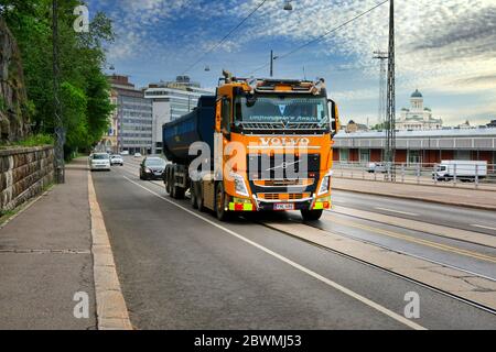 Gelb kundenspezifischen Volvo FH Kipper LKW von Suomen Vuokraurakointi Oy Fahren entlang der Straße, Stadt Landschaft Hintergrund. Helsinki, Finnland. Juni 2020. Stockfoto