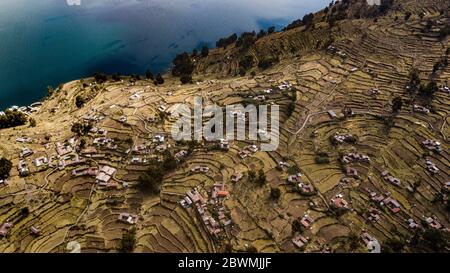 Luftaufnahme auf terrassenförmig angelegten Hängen der Insel Taquile am Titicaca-See mit anderen Inseln im Hintergrund. Der höchste schiffbare Seeblick der Welt. Stockfoto