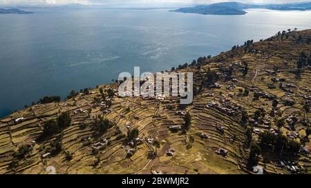 Luftaufnahme auf terrassenförmig angelegten Hängen der Insel Taquile am Titicaca-See mit anderen Inseln im Hintergrund. Der höchste schiffbare Seeblick der Welt. Stockfoto