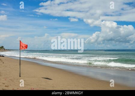 Petitenget Beach in Seminyak mit roter Flagge an sonnigen Tagen, beliebter Sunset Beach in Bali, Indonesien Stockfoto