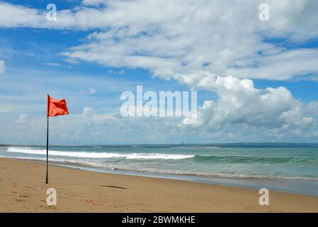 Petitenget Beach in Seminyak mit roter Flagge an sonnigen Tagen, beliebter Sunset Beach in Bali, Indonesien Stockfoto