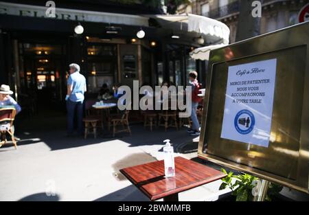 Paris, 2. Juni. Juni 2020. Ein Schild mit der Aufschrift "aus Sicherheitsgründen bitte warten Sie hier" und eine Flasche Desinfektionsgel sind vor dem Cafe de Flore in Paris, Frankreich, 2. Juni 2020 zu sehen. Frankreich hat die Sperrung des Anti-Coronavirus ab dem 2. Juni 2020 weiter aufgehoben. Restaurants, Cafés und Bars in risikoarmen Gebieten können Kunden empfangen, vorausgesetzt, sie respektieren das Gesundheitsprotokoll und die soziale Distanz. In der Region Great Paris, die als "orange" Zone eingestuft ist, können sie nur Außenräume öffnen, um ein Wiederaufleben der Epidemie zu vermeiden. Kredit: Gao Jing/Xinhua/Alamy Live News Stockfoto