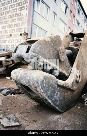 Eine schwere Betonschere, die als Baggeraufsätze verwendet wird, liegt auf dem Boden auf einer Abbruchstelle. Stockfoto