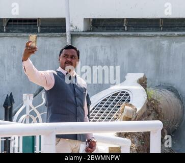 Nagpur, Maharashtra, Indien - März 2019: Ein ehrliches Porträt eines indischen Mannes, der ein Selfie vor dem buddhistischen Pilgerort Deekshabhoomi macht. Stockfoto