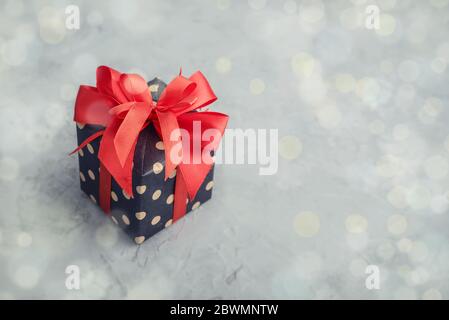 Polka dot Geschenkbox mit rotem Band auf grauem Hintergrund Nahaufnahme Stockfoto