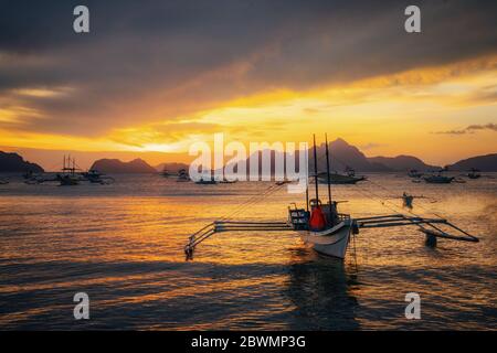 Traditionelle philippinische Boote in Corong-Corong Strand in El Nido bei Sonnenuntergang leuchten. Palawan, Philippinen Stockfoto